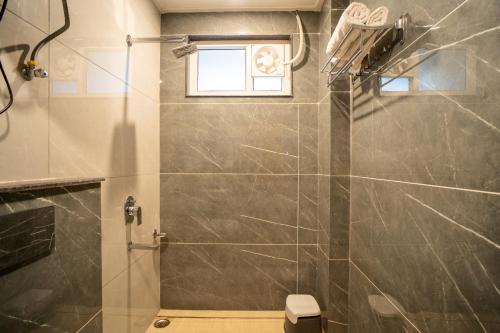 a bathroom with a shower with a toilet and a window at Winterfell Stays Mussoorie in Mussoorie