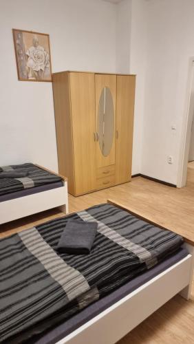 a bedroom with two beds and a wooden cabinet at Monteurwohnung 3 Bitterfeld in Bitterfeld