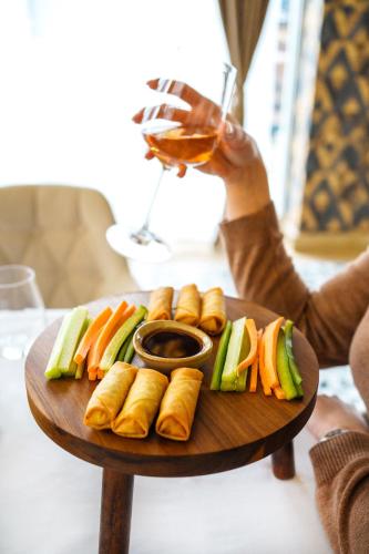 a person holding a glass of wine and a plate of sushi at Hotel Monogram Park in Ruma