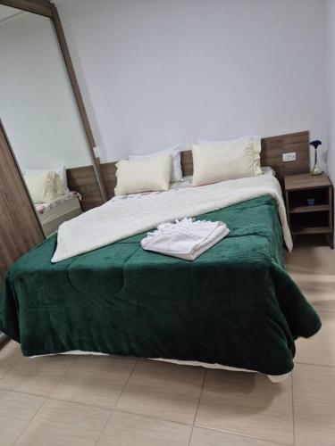 a bed with a green blanket and white towels on it at Loft, seu espaço com conforto in Mogi das Cruzes