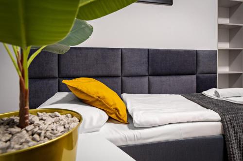 a bedroom with a bed with yellow pillows and a plant at Great Polonia Dwarf Wrocław in Wrocław