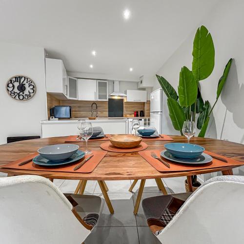 - une cuisine avec une table en bois, des assiettes et des verres à vin dans l'établissement Charmant T3 avec climatisation proche Narbonne, à Cuxac-dʼAude