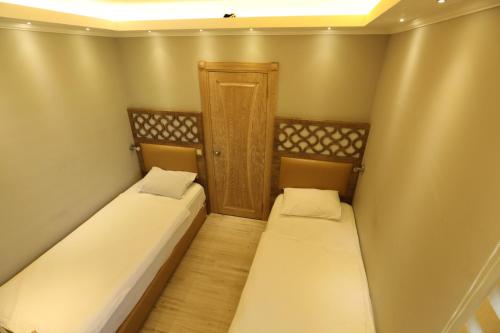 two beds in a small room with a door at Unluselek Hotel in Anamur