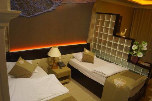 a hotel room with two beds and a lamp at Unluselek Hotel in Anamur
