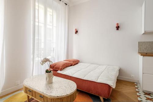 une chambre blanche avec un lit et une table dans l'établissement Appartement 50 m² lumineux et refait à neuf, à Paris