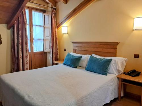 a bedroom with a white bed with blue pillows at Hotel San Roque in Reinosa