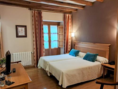 a bedroom with a bed and a desk and a window at Hotel San Roque in Reinosa