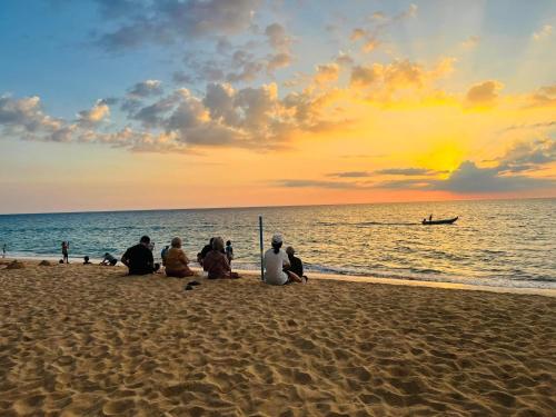 a group of people sitting on the beach watching the sunset at Turtle Tales-Tahnu,Thaimueang beach,Phang-Nga in Thai Muang