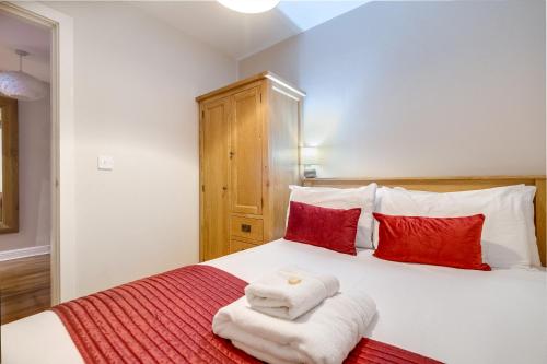 a bedroom with a bed with red and white towels on it at The Jewellery Suites Birmingham in Birmingham