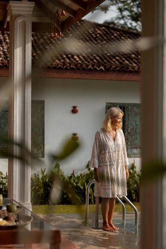 a woman standing on a chair in front of a house at Emel's Retreat By Tropical Magnum - Luxury Boutique Villa in Anhandigoda