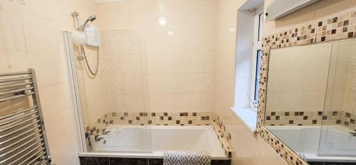 a white bathroom with a tub and a shower at Passage East Holiday Home by Trident Holiday Homes in Passage East