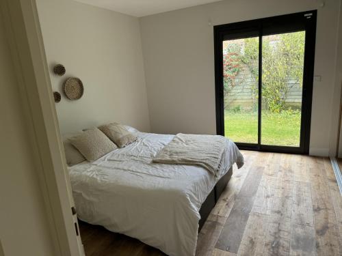 a bedroom with a bed and a large window at Maison familiale LA ROCHELLE in LʼHoumeau