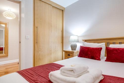 a bedroom with a large bed with red pillows at The Jewellery Suites Birmingham in Birmingham