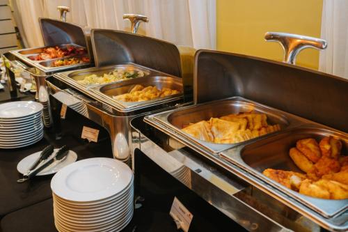 a buffet with several trays of food on a table at Hotel Cristal Białystok in Białystok