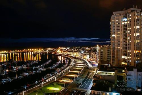 a city at night with cars parked in a parking lot at Solmar Lodge in Ponta Delgada