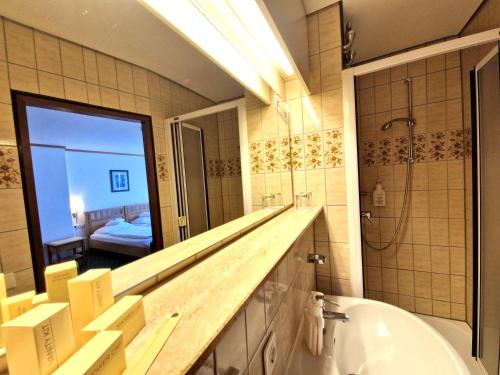 a bathroom with a tub and a large mirror at Badhotel Restaurant Stauferland in Bad Boll