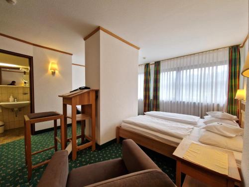 a hotel room with a bed and a desk at Badhotel Restaurant Stauferland in Bad Boll