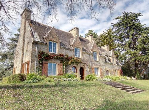 une vieille maison en pierre sur un champ herbeux dans l'établissement Ar Maner - Grande maison familiale - 7 chambres - Jardin, à Crozon