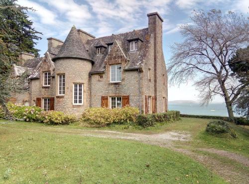 une vieille maison en pierre sur un champ herbeux dans l'établissement Ar Maner - Grande maison familiale - 7 chambres - Jardin, à Crozon