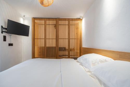 a bedroom with two beds and a flat screen tv at Skepi Town Houses in Mikonos