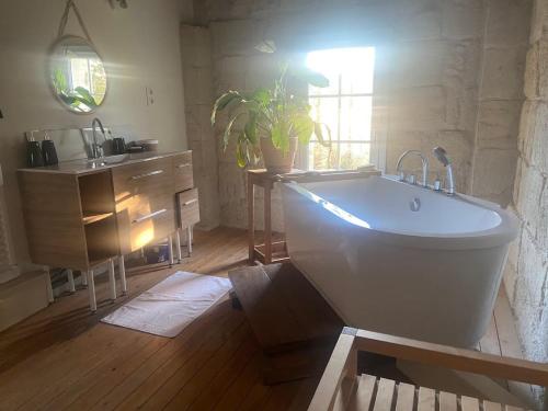 a bathroom with a white tub and a sink at La Belle Verte in Laruscade