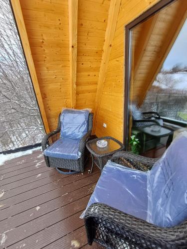 a porch with two chairs and a table on a deck at CABANA 365 in Braşov