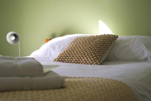 a bed with white sheets and pillows and a lamp at Hawkwood in Stroud