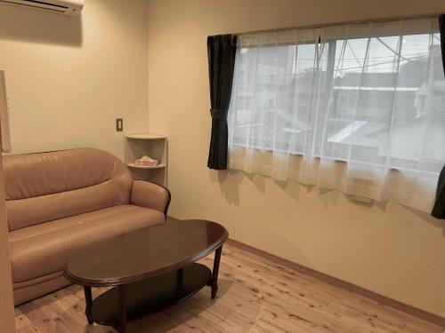 a living room with a couch and a table and a window at Shioya Hostel in Akune