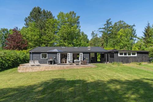 a black house with a patio and a yard at Lovely Secluded Cottage In Dronningmølle in Dronningmølle