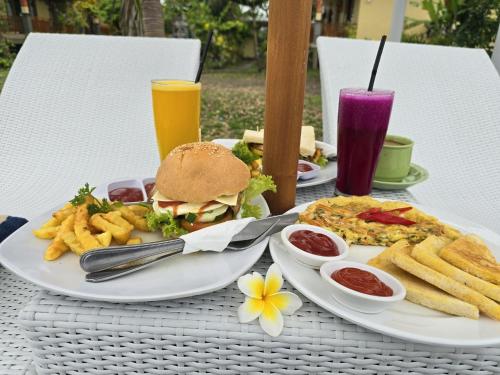 a table with plates of food and a sandwich and french fries at Kelingking BMS Penida Hills Villa in Nusa Penida