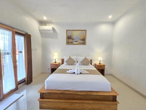 a bedroom with a large white bed with two lamps at Kelingking BMS Penida Hills Villa in Nusa Penida