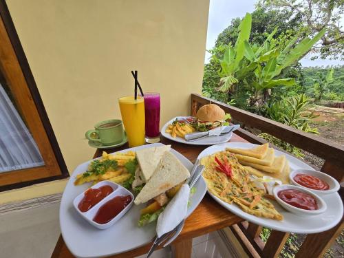 a table with two plates of food and a drink at Kelingking BMS Penida Hills Villa in Nusa Penida