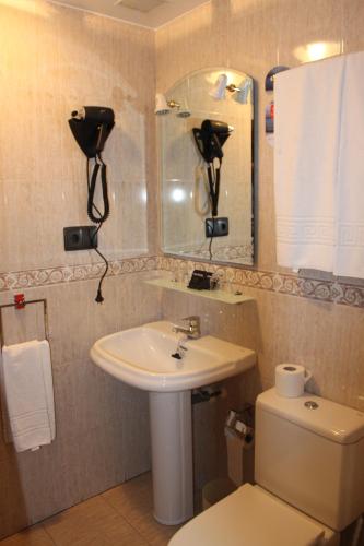 a bathroom with a sink and a toilet and a mirror at Hotel Valdés in Gijón