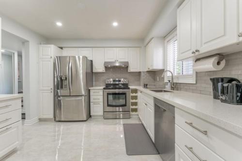 a kitchen with white cabinets and a stainless steel refrigerator at Whitby Family Retreat Comfort and Convenience in Whitby