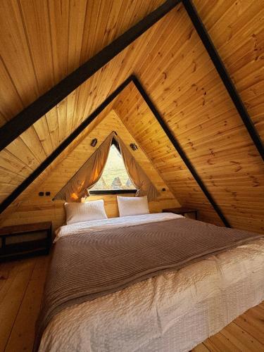 a bed in a wooden room with a window at Outdoor Cottages Kazbegi in Kazbegi
