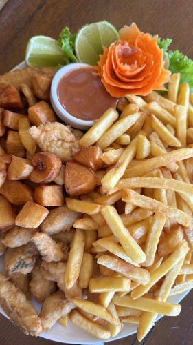 a pile of french fries on a plate with sauce at Hotel Paraiso Tropical in Alcobaça