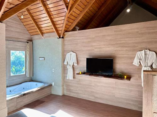 a bathroom with a tub and a flat screen tv at Chalé Suíco Nupcial III - Chalés Belo Monte in Pacoti