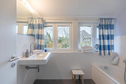 a white bathroom with a sink and a tub and a window at Dat Reethuus in Böhl