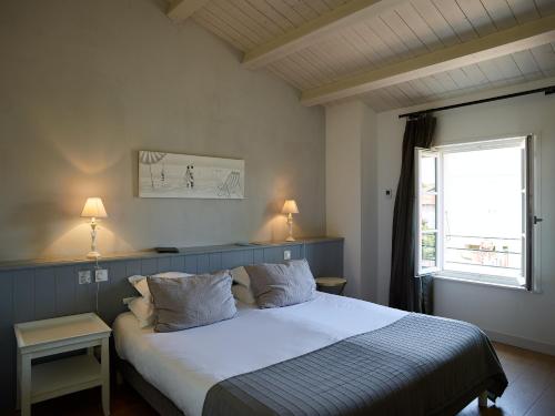 a bedroom with a large white bed with a window at Le Clos Du GALION - Ile de Ré in Saint-Martin-de-Ré