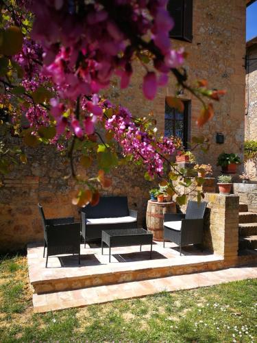 a patio with chairs and a table and flowers at CLAUDIA VACANZA TOSCANA - Appartamento Nocciolo- 10 min da Siena in Malignano