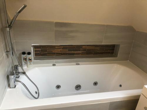 a white bath tub with a shower in a bathroom at 2-Bed Cottage Sleeps 4 10 mins to Glasgow Centre in Glasgow