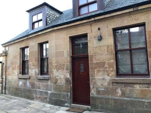 an old brick building with a brown door and windows at 2-Bed Cottage Sleeps 4 10 mins to Glasgow Centre in Glasgow