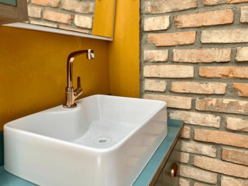 a white sink in a bathroom next to a brick wall at Casa Saíra in Bombinhas