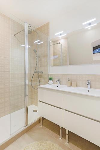 une salle de bain blanche avec une douche et un lavabo dans l'établissement La Maison du Gardien, à Brignais