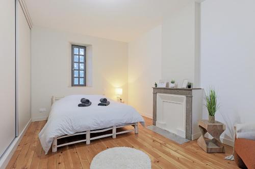 une chambre blanche avec un lit et une cheminée dans l'établissement La Maison du Gardien, à Brignais