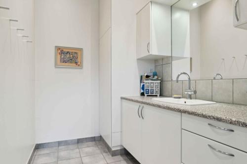 a white kitchen with a sink and a mirror at Lovely Holiday Home In Nykøbing Sjælland in Nyrup