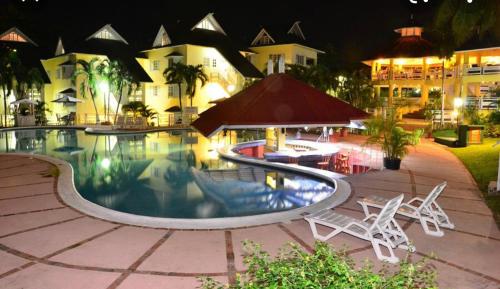 a swimming pool with chairs and tables and buildings at Mystical Studios King in Ocho Rios