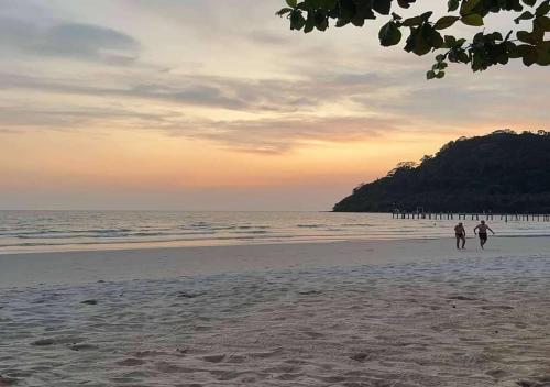 two people walking on the beach at sunset at Koh Kood AYA Homestay in Ko Kood