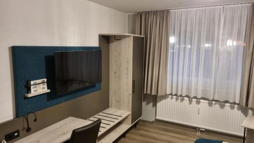 ウンナにあるAkzent Hotel Gut Höingのテレビとテーブルと窓のある部屋