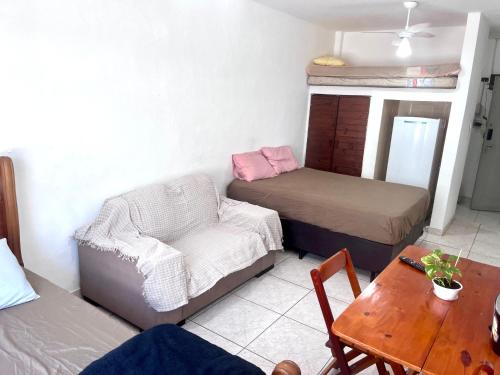 a room with a couch and a bed and a table at Kit do ALEX - AVIAÇÃO - a uma esquina da praia - Ar Condicionado in Praia Grande